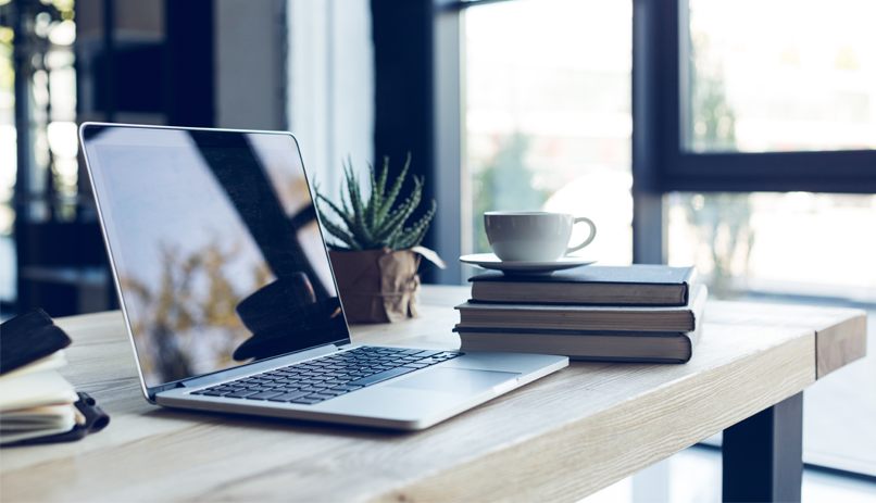 Imagem Amboente home office com mesa, computador e cadeira ao lado de uma janela