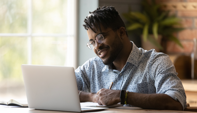 Homem negro olhando a tela do computador sorrindo